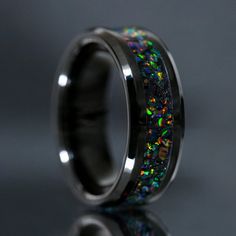 a black ring with multicolored opal inlays on the inside of it