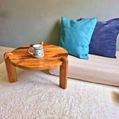 a wooden coffee table sitting on top of a white carpeted floor next to pillows