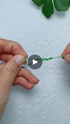 two hands are holding a green string with one hand and the other is pulling it up