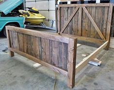 a bed frame made out of wooden planks in a garage next to a blue truck