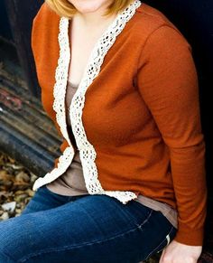 a woman sitting on the ground in front of a blue truck with pumpkin spice cardigan