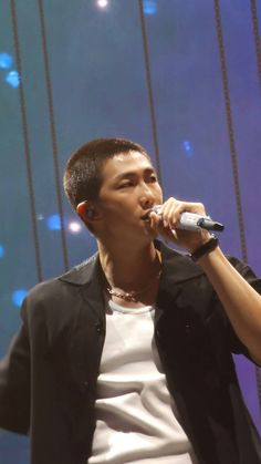 a young man holding a microphone up to his mouth as he sings into the microphone