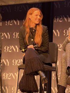 two women sitting on stools talking to each other