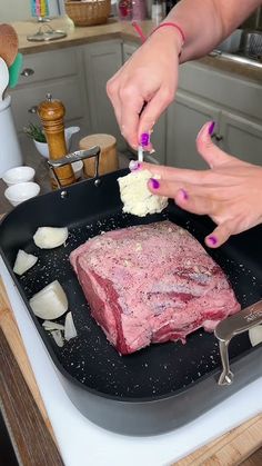 two women are cooking food in a pan on the stove top and one woman is using a knife to cut it