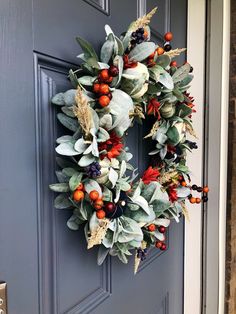 a wreath on the front door with berries and leaves hanging from it's side