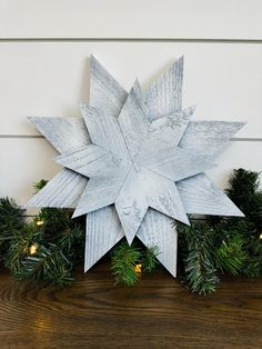 a wooden snowflake sitting on top of a table next to christmas wreaths