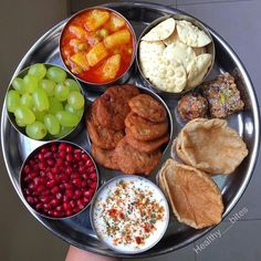 a person holding a metal tray filled with different types of food and fruit on it