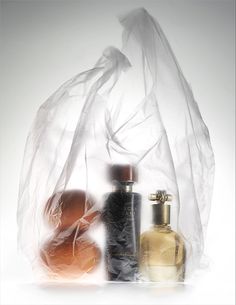 three bottles are sitting next to each other in front of a plastic bag that is filled with items