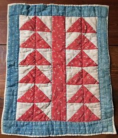 a red and white quilted table runner on top of a wooden floor next to a wall