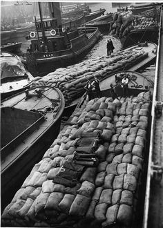 an old black and white photo of many boats in the water with sandbags on them