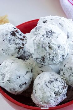 a red bowl filled with chocolate and white snowball cookies on top of a table