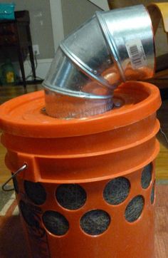 an orange trash can sitting on top of a wooden table