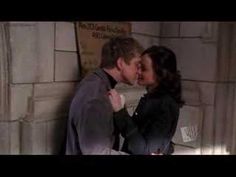 a man and woman kissing each other in front of a brick wall with candles on it