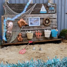 there is a wooden sign with pictures on it and other items in the sand outside