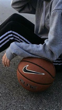 a person sitting on the ground with a basketball in front of their feet and head