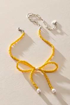 a yellow ribbon necklace with pearls on it