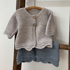 a crocheted sweater and pants are hanging on a wooden ladder next to a wall