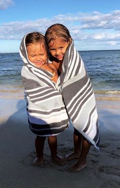 two young children wrapped in blankets on the beach