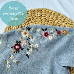 an embroidered shirt with flowers on it sitting next to a woven basket and the words, sweater embroidery pattern