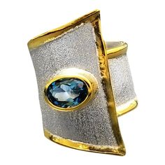 Presenting Yianni Creations Midas Collection 100% handmade artisan ring from fine silver 950 purity plated with palladium features 1.60 Carat oval cut London blue topaz. Liquid edges are decorated with a thick overlay of 24 Karat yellow gold. This wide triangular-shaped ring adjusts in size. Contact us to verify the size or if you are requesting this design in a different color variation or stone setting. Matching items available. For a full selection of Yianni Creations (YC) jewelry please visi Egypt Jewelry, Wire Jewelry Rings, Gold For Sale, Wide Band Ring, Artisan Rings, Contemporary Ring, Stone Setting, Wide Band Rings, Handcrafted Rings