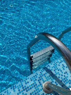 an empty swimming pool with steps leading to the water's edge and blue tiles on the floor