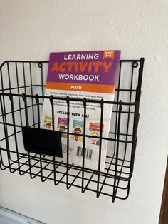 a black wire basket with a book on the front and an activity workbook in it