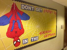 a large spiderman poster on the side of a school wall with words written below it