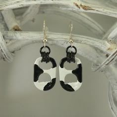 black and white cat shaped earrings hanging from a branch