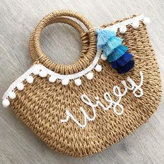 a straw bag with blue tassels and the word sew is on it