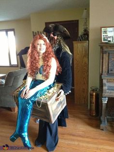 a woman with long red hair sitting on top of a suitcase next to a man