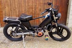 a motorcycle parked in front of a wooden fence with a small toy on the ground