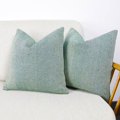 two pillows sitting on top of a white couch