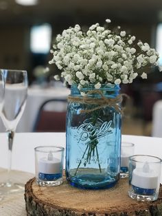 a mason jar filled with baby's breath sitting on top of a tree stump