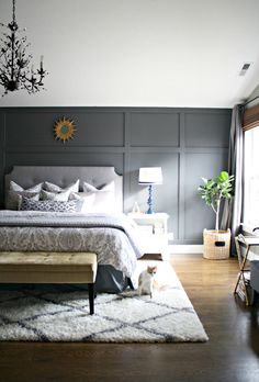 a bed room with a neatly made bed and a dog sitting on the floor next to it