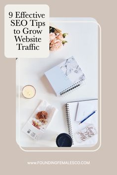 a white desk topped with notebooks and flowers next to a candle on top of it