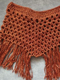 an orange crocheted shawl with fringes