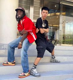 two young men sitting on the steps in front of a building