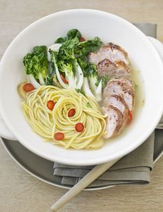 a white bowl filled with noodles, meat and veggies