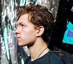 a young man standing in front of a wall with blue and green paint on it