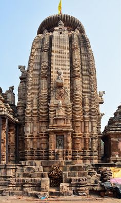 an old stone structure with statues on the sides and a yellow flag at the top