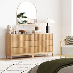 a bedroom scene with focus on the dresser and bed in the foreground as well as a mirror