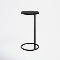 a small black table with a round base on it's side, against a white background