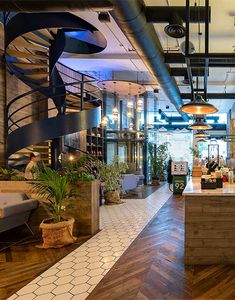 the inside of a restaurant with wooden floors and spiral staircases, potted plants on either side of the counter