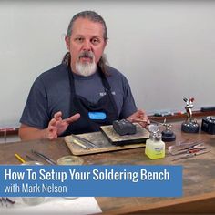 a man sitting at a table with tools in front of him and the words how to setup your soldering bench