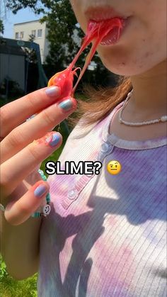 a girl with pink and blue nail polish holding an object in her hand that says, slime?