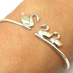 "Silver Mother and Child Swan Bracelet is handmade with its own uniqueness. It can be bought as a gift for any occasion like birthday gift, wedding gift, travel gift, souvenir and etc. If you need rose gold plating or yellow gold plating, please contact us, we will advice you on the additional fees applicable. Base Material: Sterling Silver Size: 15mm (Approximately) Bangle wrist size: Adjustable / Please give us your wrist circumference. Thickness: 1.5mm / 0.059 Inch Metal Stamped: 925 Crafting Swan Bracelet, Swan Bird, Engagement Ring Holders, Baby Pony, Ring Holder Necklace, Couple Necklaces, Girl Friend, Horse Lovers, Bird Jewelry