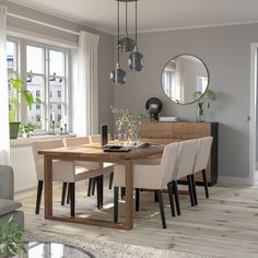 a dining room table with chairs and a laptop computer on it, in front of a window