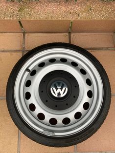 the front wheel of a volkswagen car is seen from above on a brick flooring area