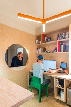 a man sitting at a desk in front of a computer monitor on top of a green chair