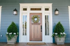 a front door with two planters and a wreath on it